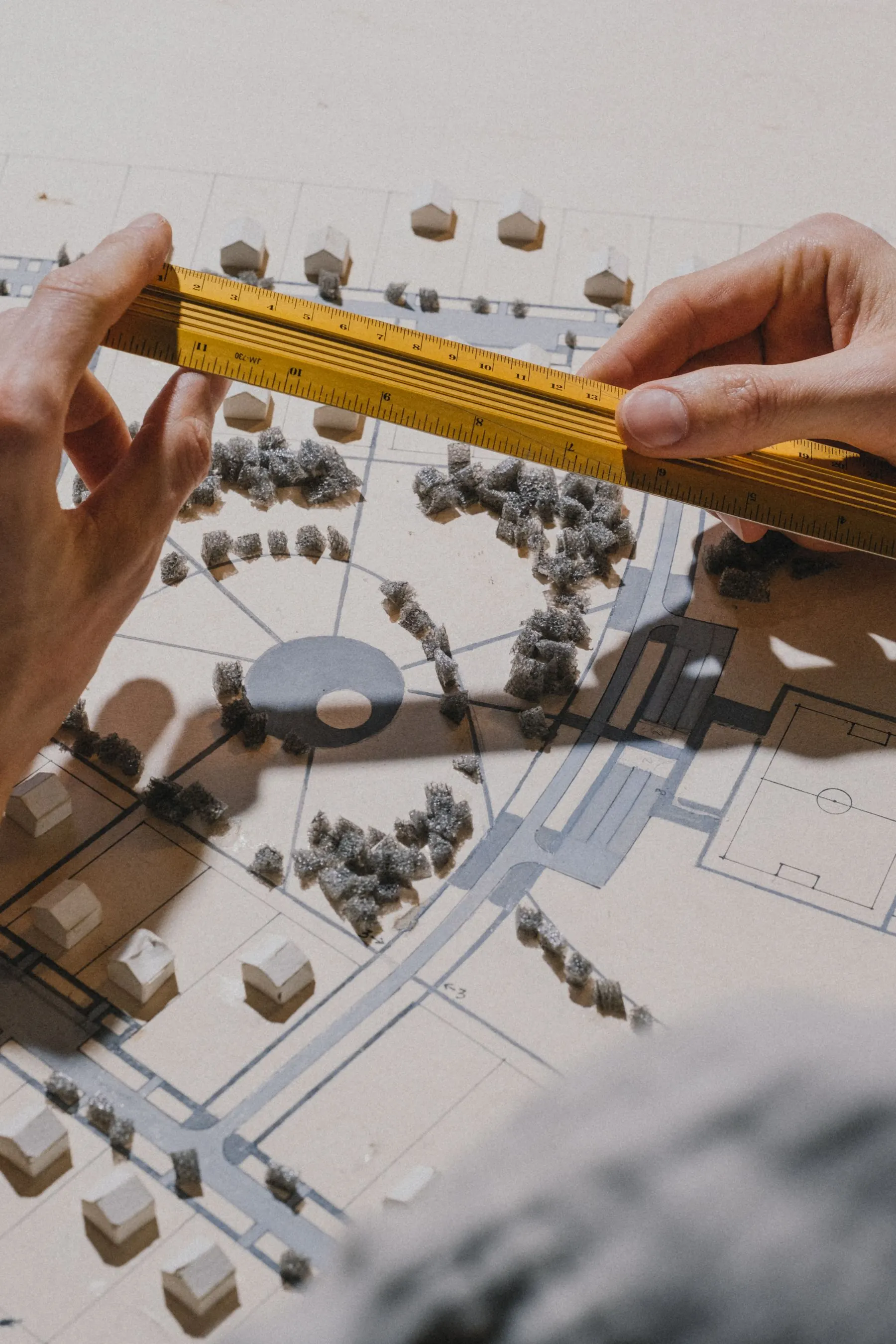 Hands measuring an architectural model with precision